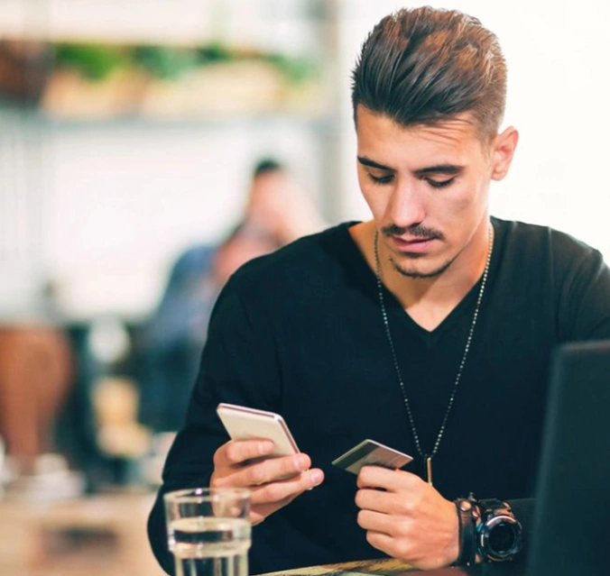 A man sitting at a table looking at his phone.