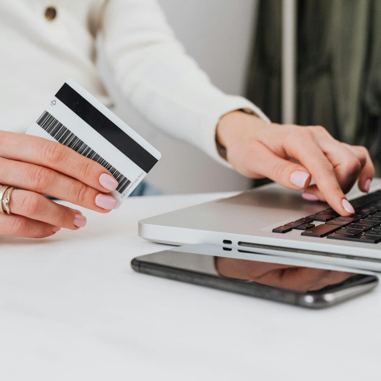 A person holding a credit card and using a laptop.