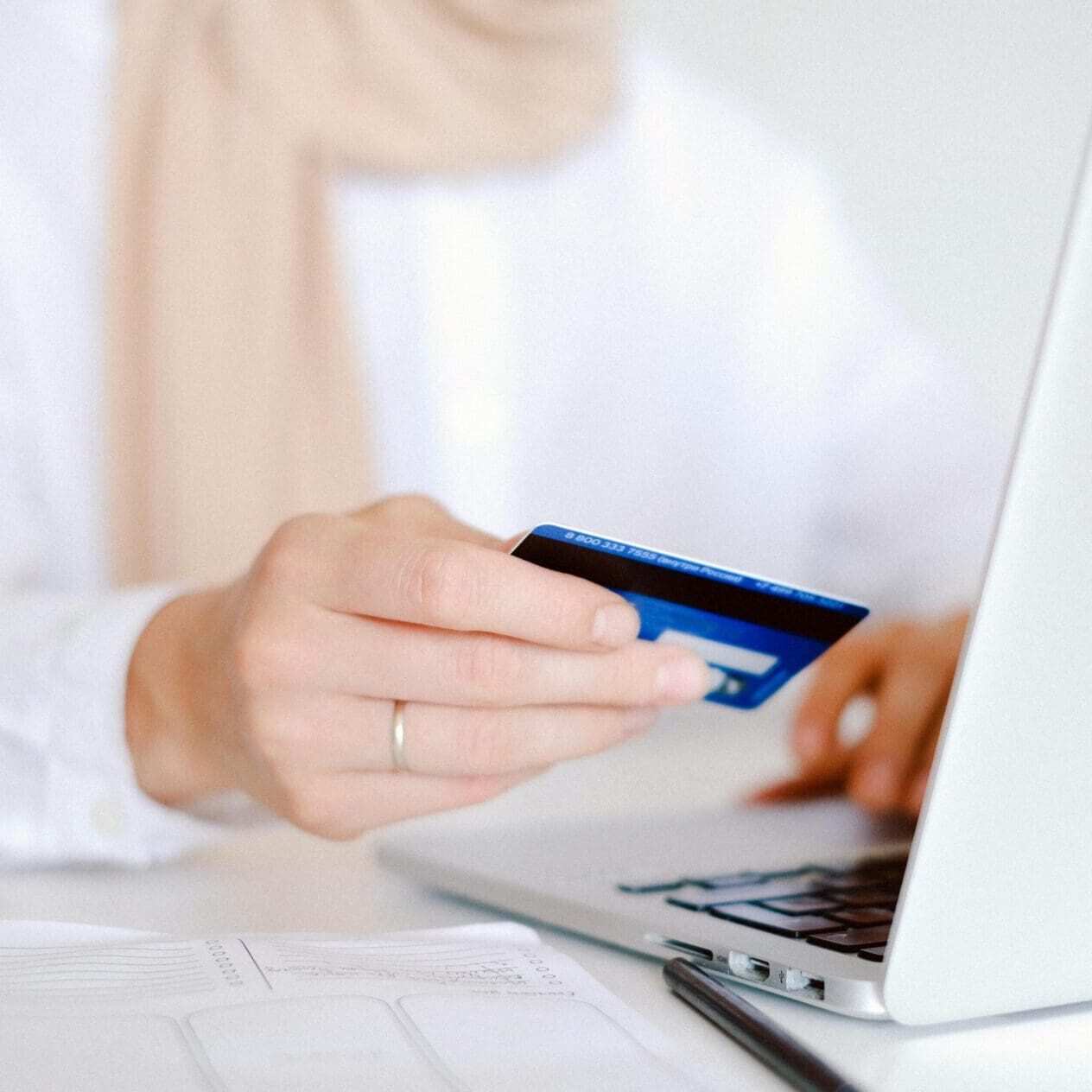 A person holding their credit card while using a laptop.